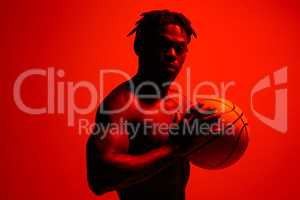 Expect great things of yourself. Red filtered shot of a young sportsman posing with a basketball in the studio.