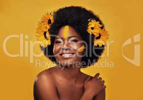 Sunflowers speak to me best. Studio portrait of a beautiful young woman smiling while posing with sunflowers in her hair against a mustard background.