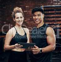Check out our website for awesome workout routines. two sporty young people holding a digital tablet in the gym.