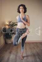 Flexibility is the goal. Full length shot of an attractive young woman standing and holding an advanced yoga pose during an indoor yoga session.