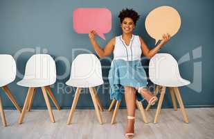 I have some exciting news to tell you. Studio portrait of an attractive young businesswoman holding up speech bubbles while sitting in line against a grey background.