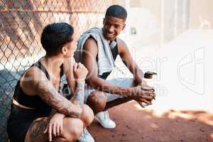 Just happy to be hanging. two sporty young people chatting to each other against a fence outdoors.