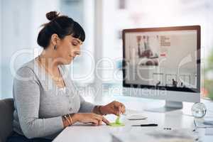 Note-taking is essential to goal setting. an attractive young businesswoman sitting alone in her office and using post-its to make notes.