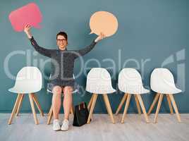 I have two big announcements to make. Studio portrait of an attractive young businesswoman holding up speech bubbles while sitting in line against a grey background.