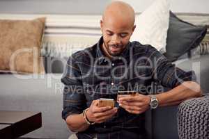 I can pay all my bills from the comfort of my home. a young man using his credit card while using his cellphone.