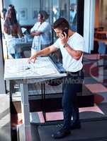 Burning some calories while making some deals. a young businessman talking on a cellphone and going through paperwork while walking on a treadmill in an office.