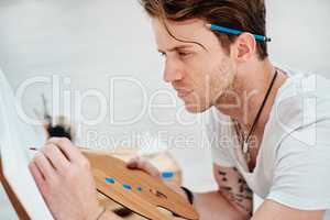 Art is a path to self-discovery. a handsome young artist sitting and looking contemplative during an art class in the studio.