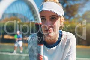 Train like a champion if you want to become one. an attractive young female tennis player outdoors on the court with her male teammate in the background.