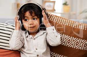 I know a good song when I hear one. an adorable little boy listening to music on headphones while sitting on a sofa at home.