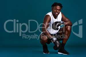 Confidence breeds my strength. Full length portrait of a handsome young boxer crouching against a dark background with his boxing gloves on.