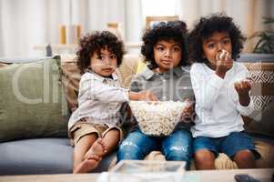 Boys will be boys. three adorable little boys eating popcorn and watching movies together at home.