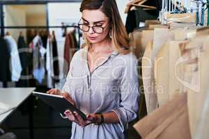 Researching current fashion trends. a young fashion designer using a digital tablet at work.