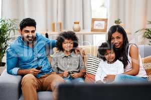 Nothing feels better than spending time with family. a beautiful young family sitting on sofa and watching tv together at home.