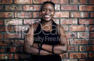 Build your body. Build your confidence. Cropped portrait of an attractive young female athlete standing with her arms crossed against a brick wall in the gym.