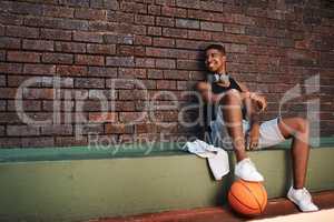 I believe in shooting for your goals. a sporty young man taking a break after a game of basketball.