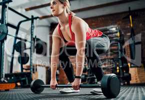 Lift with your legs. Full length shot of an attractive young female athlete working out with weights in the gym.