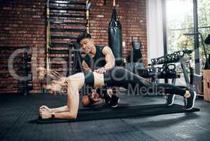 Youll never regret getting a personal trainer. a young woman working out with her personal trainer.