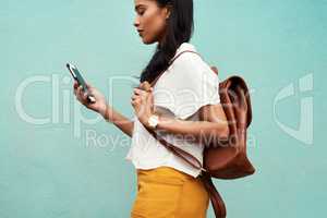 Following the maps to my next destination. an unrecognizable woman standing alone against a blue background and texting while in the city.