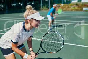 Winners never lose their focus. an attractive young female tennis player playing together with a male teammate outdoors on a court.