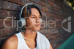 Leave me with my thoughts and music for a bit. a sporty young man listening to music outdoors.