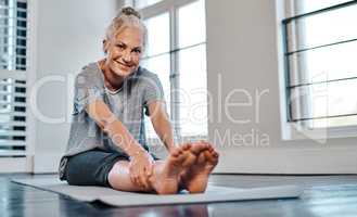 Remamber to rest in between. Portrait of a cheerful mature woman practicing yoga inside of a studio during the day.