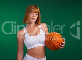 Success starts with discipline. an attractive young sportswoman standing alone and holding a basketball against a green background in the studio.