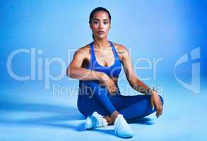 Strong minds create strong bodies. Full length shot of an attractive young sportswoman sitting down and posing against a blue background.