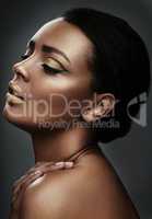 Magnify the beauty that already exists. a beautiful young woman wearing gold makeup against a grey background.