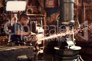 Sparks fly when metal melts. a handsome young metal worker using a blowtorch while working inside a welding workshop.