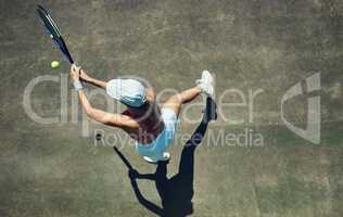 Keep swinging. High angle shot of a focused young woman playing tennis outside on a tennis court during the day.