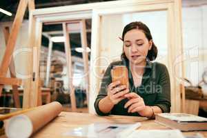 I can easily use my phone to check the calculations for my project. a female carpenter using her cellphone while sitting in her workshop.