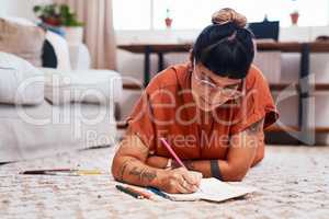 Enjoying a good stress- relief session. a young woman using coloring pens while drawing at home.