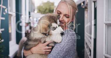 Give a dog love and hell give you loyalty. young woman cuddling her adorable husky puppy during a social gathering at home.
