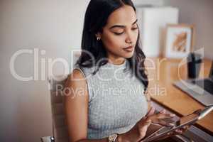 Browsing the web for something new. a young businesswoman using a digital tablet in an office.