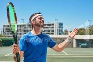 Oh come on. a handsome young man feeling frustrated while playing a game of tennis during the day.