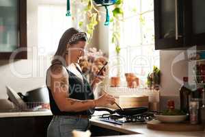 Recipe management made easier with mobile apps. a young woman using a smartphone while preparing a meal at home.