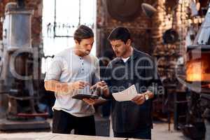 We run our workshop smart and efficiently. two handsome young using a digital tablet while working together inside their workshop.