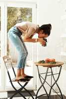 There are no limits to whats achievable with a camera. Full length shot of an attractive young businesswoman standing and using her camera to photograph cupcakes for her blog.