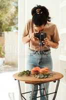 I love blogging. an attractive young businesswoman standing and using her camera to photograph cupcakes for her blog.
