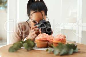 This is going to look so good on my blog. an attractive young businesswoman using her camera to photograph cupcakes for her blog.