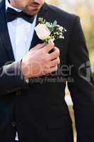 Flowers fit perfectly in any occasion of celebration. an unrecognizable young bridegroom adjusting his boutonniere and getting ready outdoors on his wedding day.