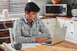 Paying on time is easier when you do it online. a man sitting with paperwork and his laptop at home.