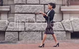 Lets bless these streets with money a little. Full length shot of an attractive young businesswoman throwing money in the air while walking outdoors in the city.