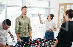 How did you lose that. a diverse group of businesspeople standing together and bonding over a game of foosball in the office.