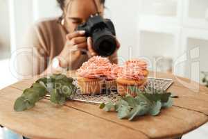 Making sure I get the right angle. an attractive young businesswoman using her camera to photograph cupcakes for her blog.