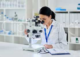 Solving medical mysteries like she does best. a young scientist using a microscope in a laboratory.