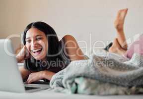 The internet has no shortage of laughs. a young woman using a laptop while relaxing in bed at home.