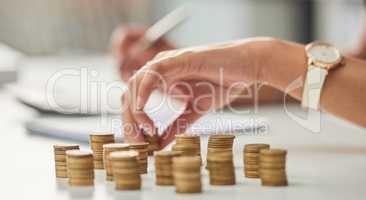 Counting those pennies. an unrecognizable businesswoman stacking coins while working in her office.
