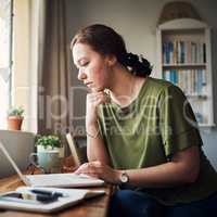 I need to find a way to increase profits. an attractive young businesswoman sitting alone in her home office and looking contemplative while using her laptop.