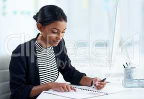 Busy people eventually turn into successful people. an attractive young businesswoman going over paperwork inside her office at work.